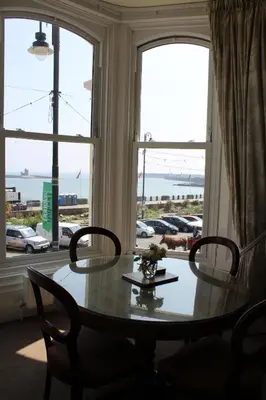 a table and chairs in a room with a window at The Town House in Douglas