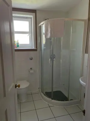 a bathroom with a shower and a toilet and a window at Barcloy Honey House in Kirkcudbright