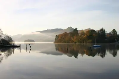 a lake with trees and a boat in the water at The Borrowdale Hotel in Keswick