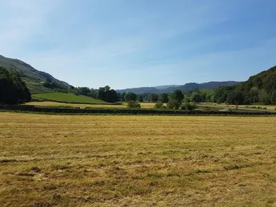 a field of grass with mountains in the background at Shepherds hut Dolly wagon in Keswick