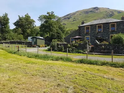 a stone house with a hill in the background at Shepherds hut Dolly wagon in Keswick
