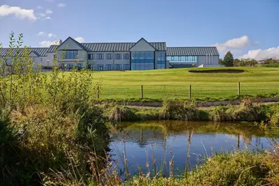 a large building with a pond in front of it at Comis Hotel & Golf Resort in Douglas
