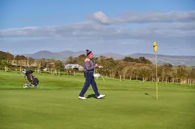 a person walking on a golf course with a ball at Comis Hotel & Golf Resort in Douglas