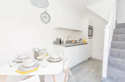 a white dining room with a white table and a clock at The Annex in Carlisle