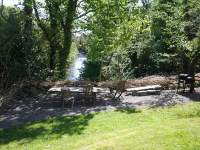 a group of chairs and a table next to a river at Doonbank Cottage Bothy in Ayr