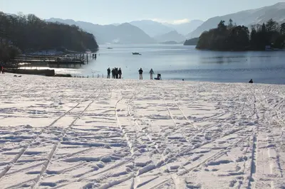 a group of people standing on a snow covered beach at West View in Keswick