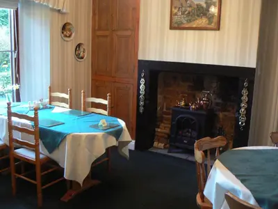 a dining room with a table and a fireplace at Forest How Guest House in Eskdale