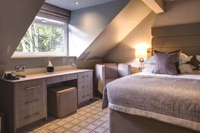 a bedroom with a bed and a desk and a window at The Grand at Grasmere in Grasmere
