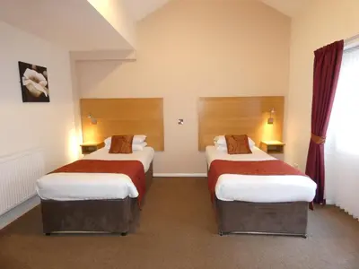 a hotel room with two beds and a window at The Old Ginn House Inn in Great Clifton
