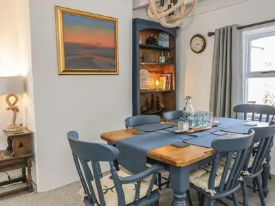 a dining room with a blue table and chairs at Marsh Villa in Skinburness