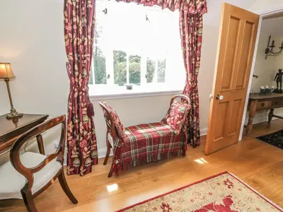 a living room with a chair and a window at Bracken Holiday Cottage in Dalbeattie