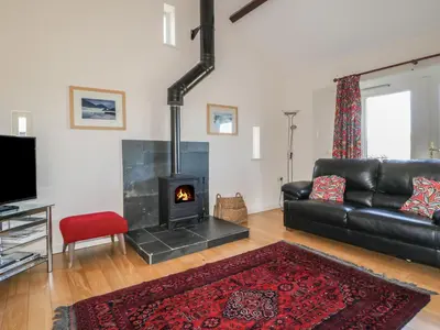 a living room with a black leather couch and a fireplace at Esthers Barn in Cockermouth