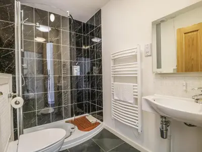 a bathroom with a shower and a sink and a toilet at Esthers Barn in Cockermouth