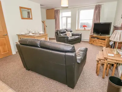 a living room with a leather couch and a television at 2 Park Nook Close in Waberthwaite