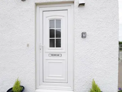 a white door on a white house with plants at 1 Park Nook Close in Waberthwaite