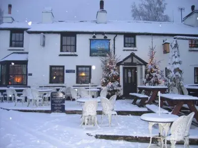 a building with tables and chairs in the snow at The Britannia Inn in Elterwater