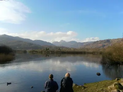 two people sitting on the edge of a lake at The Britannia Inn in Elterwater