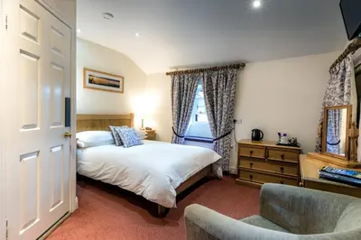 a bedroom with a bed and a chair and a window at The Britannia Inn in Elterwater