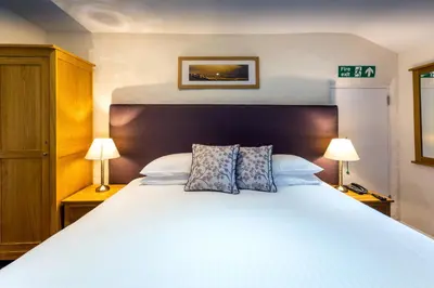 a bedroom with a large white bed with two lamps at The Britannia Inn in Elterwater