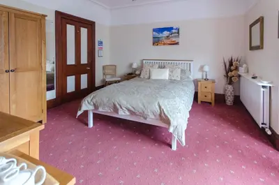 a bedroom with a bed and a pink carpet at Abacourt House in Keswick