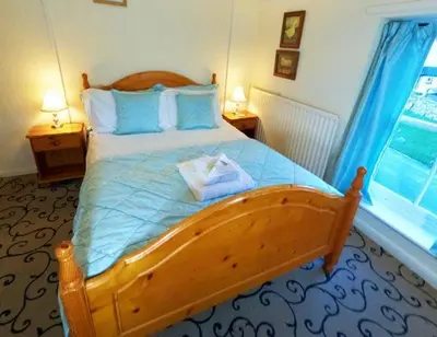 a bedroom with a large wooden bed with blue pillows at Strands Hotel/Screes Inn & Micro Brewery in Nether Wasdale