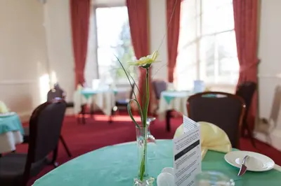 a vase with flowers sitting on a table at Woodland House Hotel in Dumfries