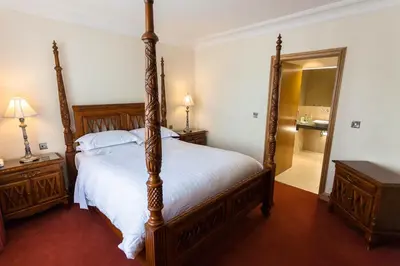 a bedroom with a large bed and a large mirror at Woodland House Hotel in Dumfries