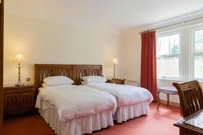a bedroom with two beds and a window at Woodland House Hotel in Dumfries