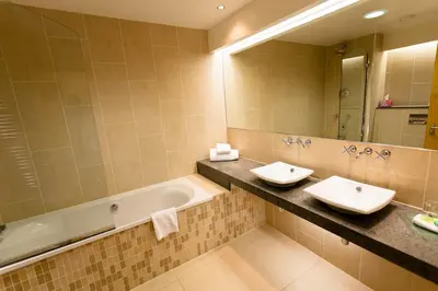 a bathroom with two sinks and a tub and a mirror at Woodland House Hotel in Dumfries