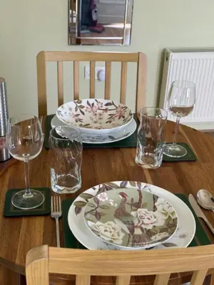 a wooden table with two plates and glasses on it at The Stables @ The Forge Cronk Y Voddy in Saint Johns