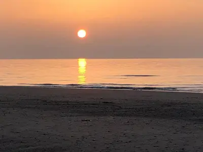 a sunset on the beach with the sun setting at The Stables @ The Forge Cronk Y Voddy in Saint Johns