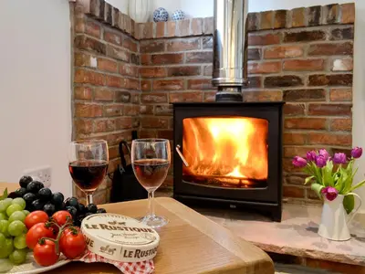 two glasses of wine on a table in front of a fireplace at Farmhouse Cottage - Uk1285 in Westward