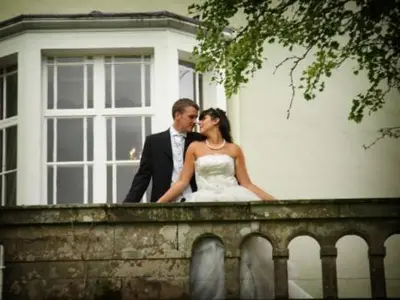 a bride and groom are standing on a fence at Overwater Hall in Bassenthwaite