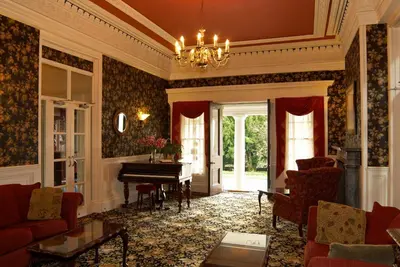 a living room with a piano and red furniture at Overwater Hall in Bassenthwaite