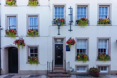 a white building with flowers in window boxes at Georgian House Hotel in Whitehaven