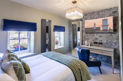 a bedroom with a bed and a desk and windows at Georgian House Hotel in Whitehaven