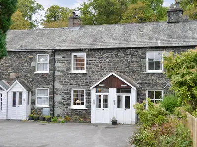 an old stone house with a white garage at Bobbin Cottage in Keswick