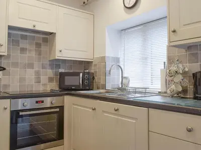 a kitchen with white cabinets and a sink and a microwave at Bobbin Cottage in Keswick