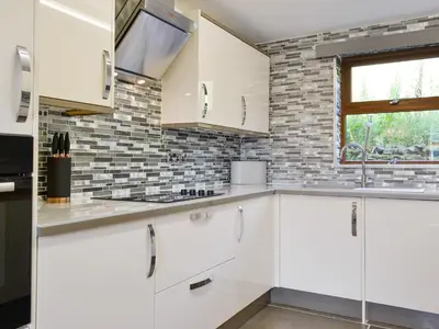 a kitchen with white cabinets and a brick wall at Grajo Cottage - Uk1284 in Threlkeld