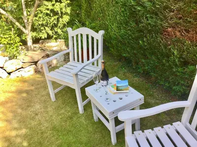 two white chairs and a table with a bottle of wine at Apple Tree Cottage in Bassenthwaite