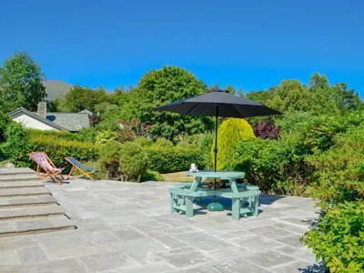 a picnic table with an umbrella on a patio at Rotherwood in Portinscale