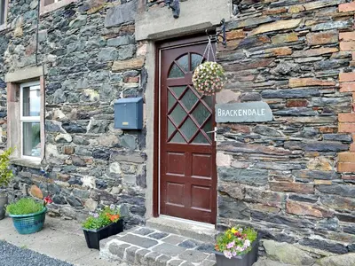 a stone building with a door with a sign on it at Brackendale Cottage - Uk1335 in Threlkeld