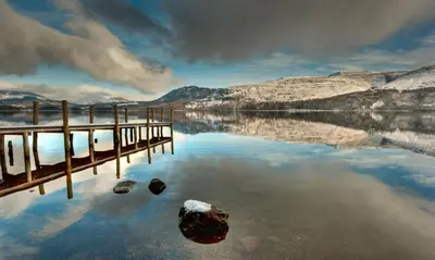 a body of water with a pier and mountains at Lords Seat Bed & Breakfast in Keswick