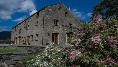 an old stone building with flowers in front of it at Lords Seat Bed & Breakfast in Keswick