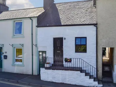 a white house with a staircase in front of it at Little Cottage in Wigtown