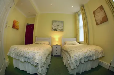 two beds in a room with yellow walls at The Devonian in Douglas