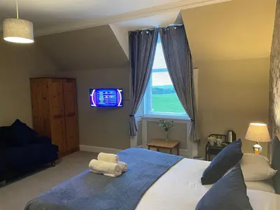 a bedroom with a large bed with a tv in the window at Ernespie House Hotel in Castle Douglas