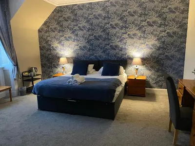 a bedroom with a bed with blue sheets and blue wallpaper at Ernespie House Hotel in Castle Douglas