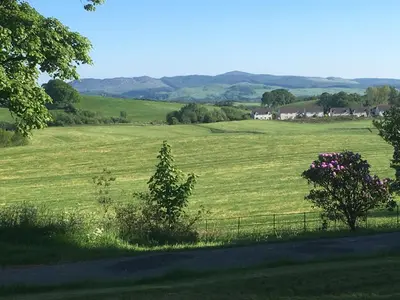 a field of green grass with houses in the distance at Ernespie House Hotel in Castle Douglas