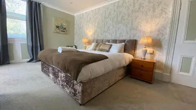 a bedroom with a large bed and a night stand with two lamps at Ernespie House Hotel in Castle Douglas